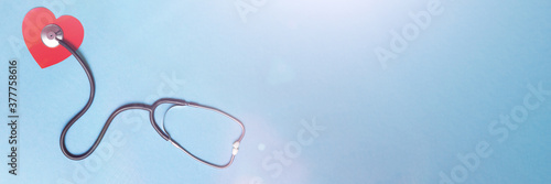 Stethoscope and red heart on blue background. Top view. Banner. Copy space. Place for text.