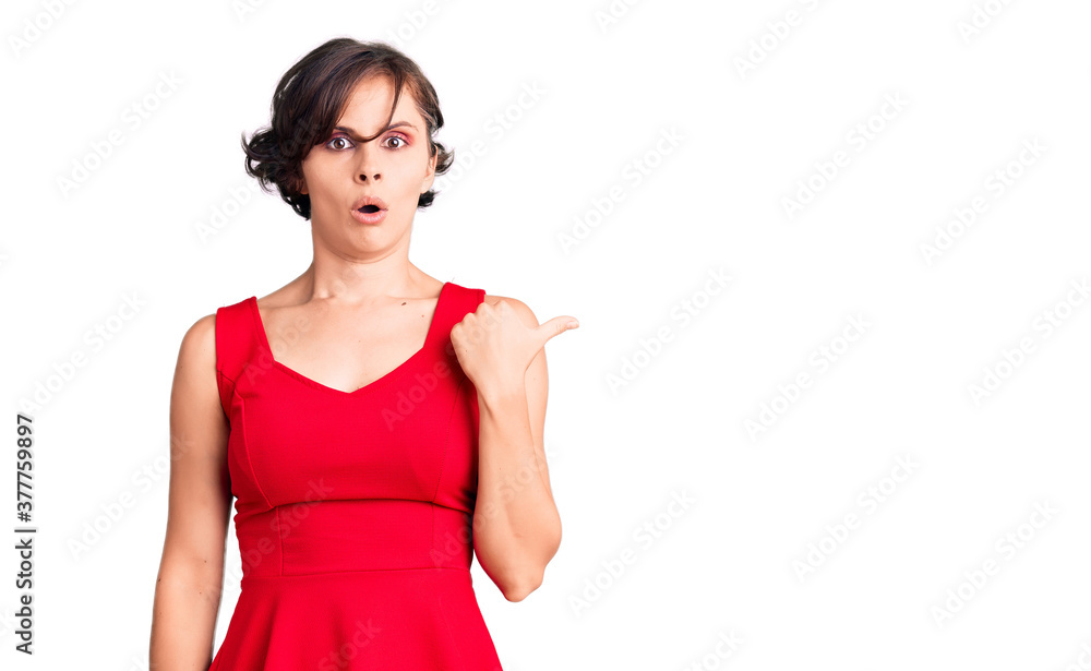 Beautiful young woman with short hair wearing casual style with sleeveless shirt surprised pointing with hand finger to the side, open mouth amazed expression. Beautiful young woman with short hair wearing casual style with sleeveless shirt surprised pointing with hand finger to the side, open mouth amazed expression.