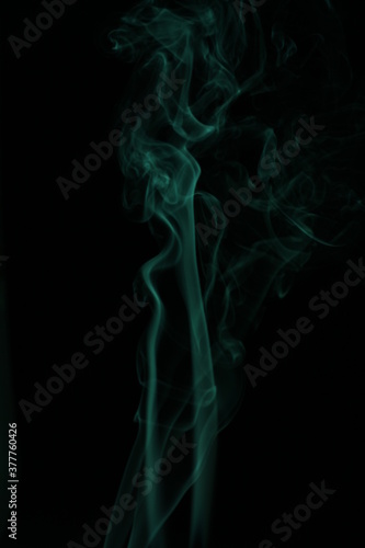 green smoke from incense on a black background