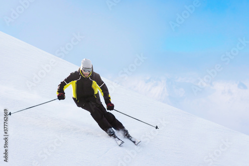 Alpine skier on piste running downhill