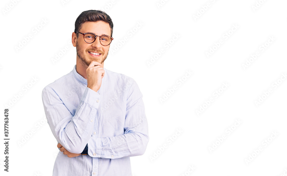 Handsome young man with bear wearing elegant business shirt and glasses looking confident at the camera smiling with crossed arms and hand raised on chin. thinking positive. Handsome young man with bear wearing elegant business shirt and glasses looking confident at the camera smiling with crossed arms and hand raised on chin. thinking positive.