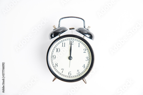 black alarm clock with white dial, 12 o'clock, isolate on white