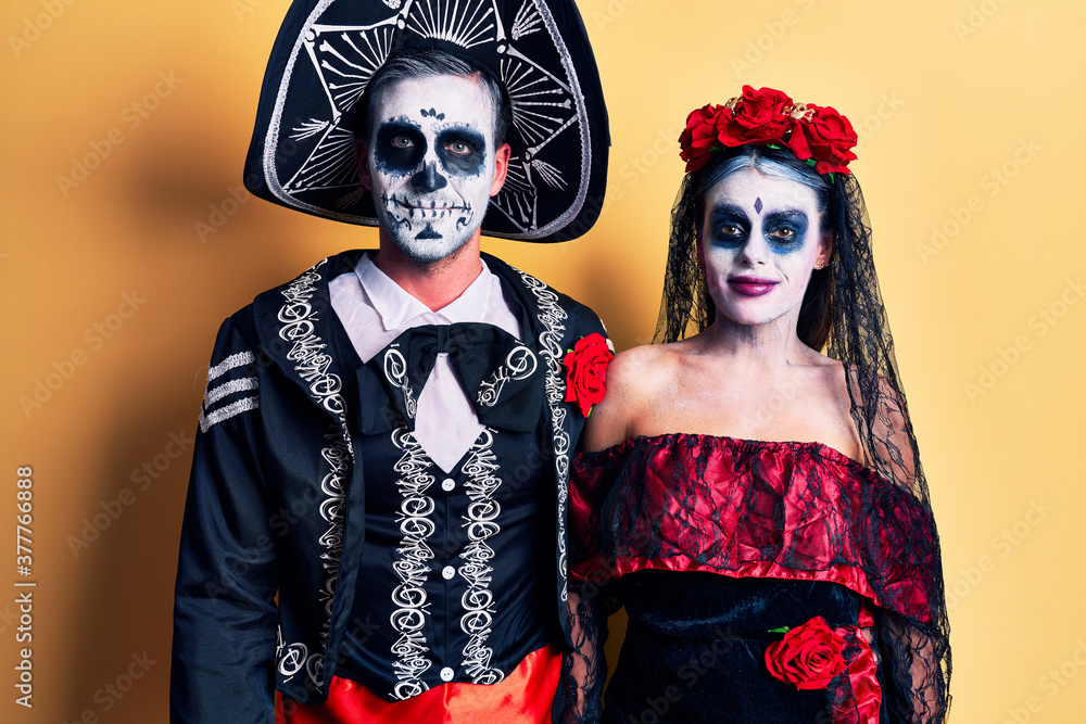 Young couple wearing mexican day of the dead costume over yellow with a happy and cool smile on face. lucky person.