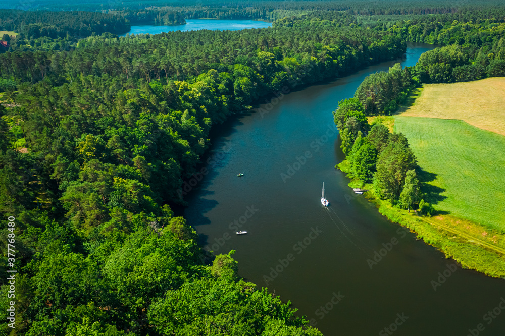 White boat on a river among forests in summer, Poland