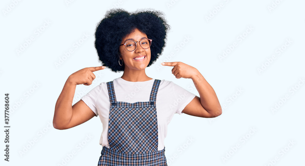 Young african american girl wearing casual clothes smiling cheerful showing and pointing with fingers teeth and mouth. dental health concept. Young african american girl wearing casual clothes smiling cheerful showing and pointing with fingers teeth and mouth. dental health concept.