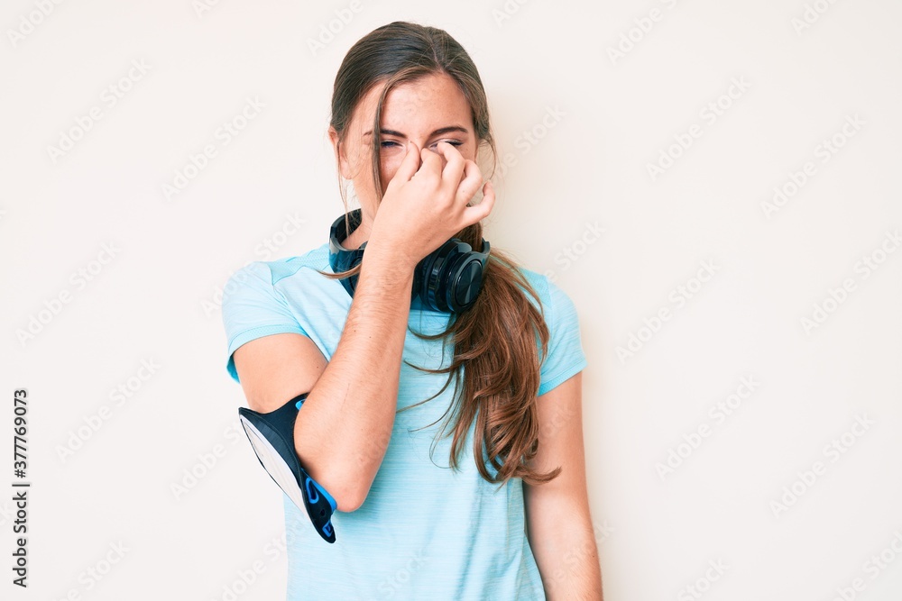 Beautiful young caucasian woman wearing gym clothes and using headphones tired rubbing nose and eyes feeling fatigue and headache. stress and frustration concept. Beautiful young caucasian woman wearing gym clothes and using headphones tired rubbing nose and eyes feeling fatigue and headache. stress and frustration concept.