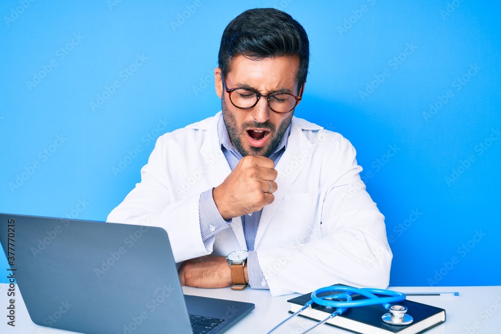 Young hispanic man wearing doctor uniform working at the clinic feeling unwell and coughing as symptom for cold or bronchitis. health care concept. - obrazy, fototapety, plakaty 