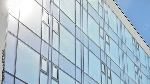 Blue curtain wall made of toned glass and steel constructions under blue sky. A fragment of a building.