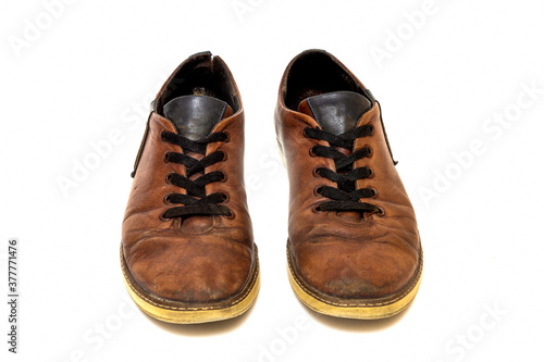 Old dirty brown leather shoes on an isolated white background. Concept, second hand, hard work, walking, worn out pair of lace-up low shoes.