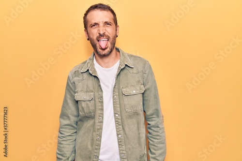 Young handsome man wearing casual clothes sticking tongue out happy with funny expression. emotion concept.