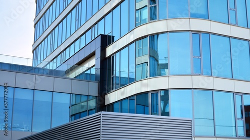 Blue curtain wall made of toned glass and steel constructions under blue sky. A fragment of a building.