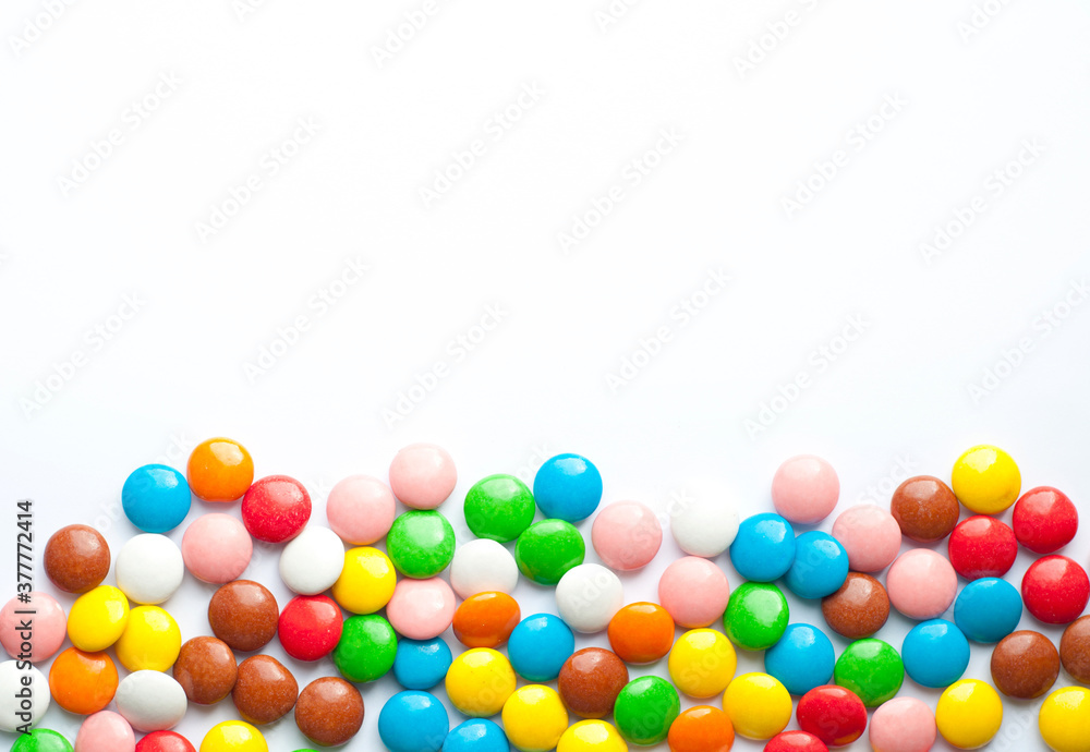 Colored balls of sugar on a white background. Chocolate candies covered with multicolored sugar glaze. Place for text Colored balls of sugar on a white background. Chocolate candies covered with multicolored sugar glaze. Place for text