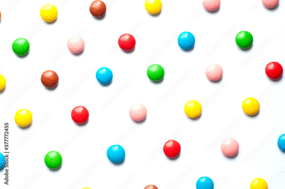 Colored balls of sugar on a white background. Chocolate candies covered with multicolored sugar glaze.
