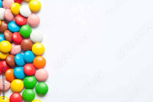 Colored balls of sugar on a white background. Chocolate candies covered with multicolored sugar glaze. Place for text