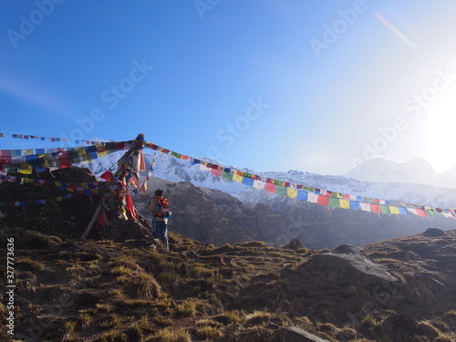 A climber staring at Talcho (Tibetan praying flags) under a blue sky, ABC (Annapurna Base Camp) Trek, Annapurna, Nepal