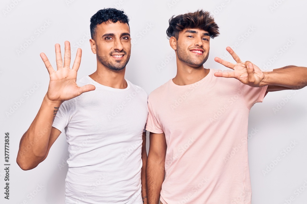 Young gay couple wearing casual clothes showing and pointing up with fingers number eight while smiling confident and happy. Young gay couple wearing casual clothes showing and pointing up with fingers number eight while smiling confident and happy.