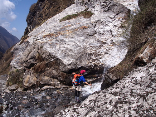 A climber taking a splash of water from a large rock, ABC (Annapurna Base Camp) Trek, Annapurna, Nepal