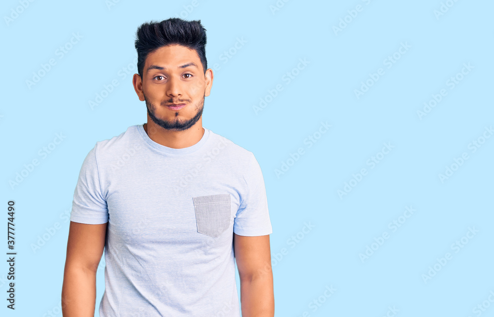 Handsome latin american young man wearing casual clothes puffing cheeks with funny face. mouth inflated with air, crazy expression. Handsome latin american young man wearing casual clothes puffing cheeks with funny face. mouth inflated with air, crazy expression.