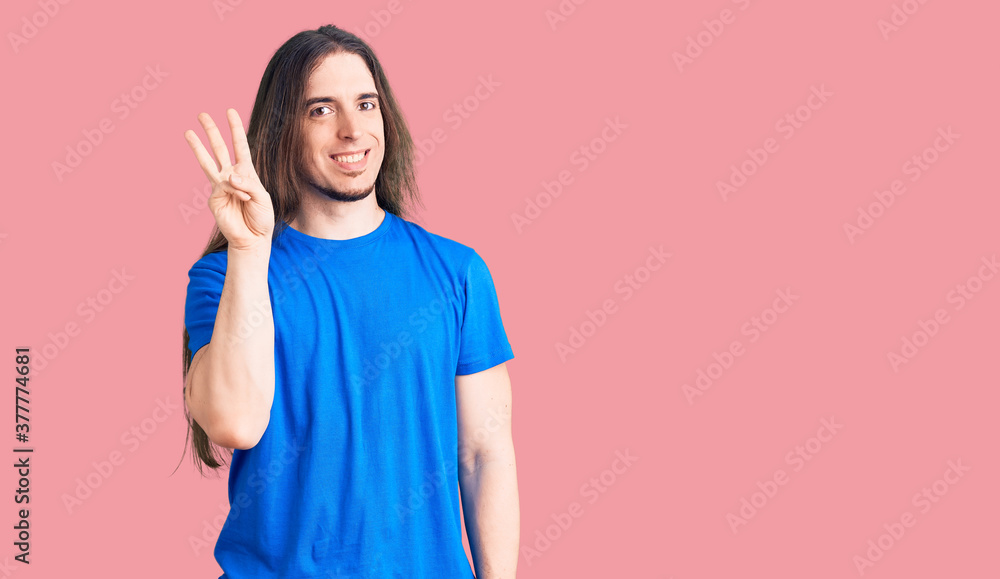 Young adult man with long hair wearing swimwear showing and pointing up with fingers number three while smiling confident and happy. Young adult man with long hair wearing swimwear showing and pointing up with fingers number three while smiling confident and happy.
