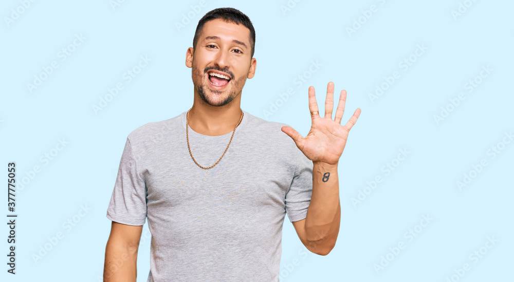 Handsome man with tattoos wearing 90s style showing and pointing up with fingers number five while smiling confident and happy. Handsome man with tattoos wearing 90s style showing and pointing up with fingers number five while smiling confident and happy.