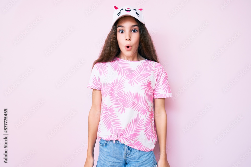 Cute hispanic child girl wearing casual clothes and funny kitty cap scared and amazed with open mouth for surprise, disbelief face Cute hispanic child girl wearing casual clothes and funny kitty cap scared and amazed with open mouth for surprise, disbelief face