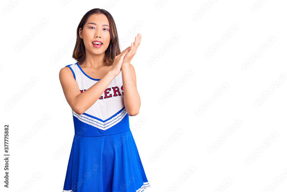 Young beautiful chinese girl wearing cheerleader uniform clapping and applauding happy and joyful, smiling proud hands together Young beautiful chinese girl wearing cheerleader uniform clapping and applauding happy and joyful, smiling proud hands together