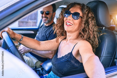 Middle age beautiful couple on vacation wearing sunglasses smiling happy driving car. © Krakenimages.com