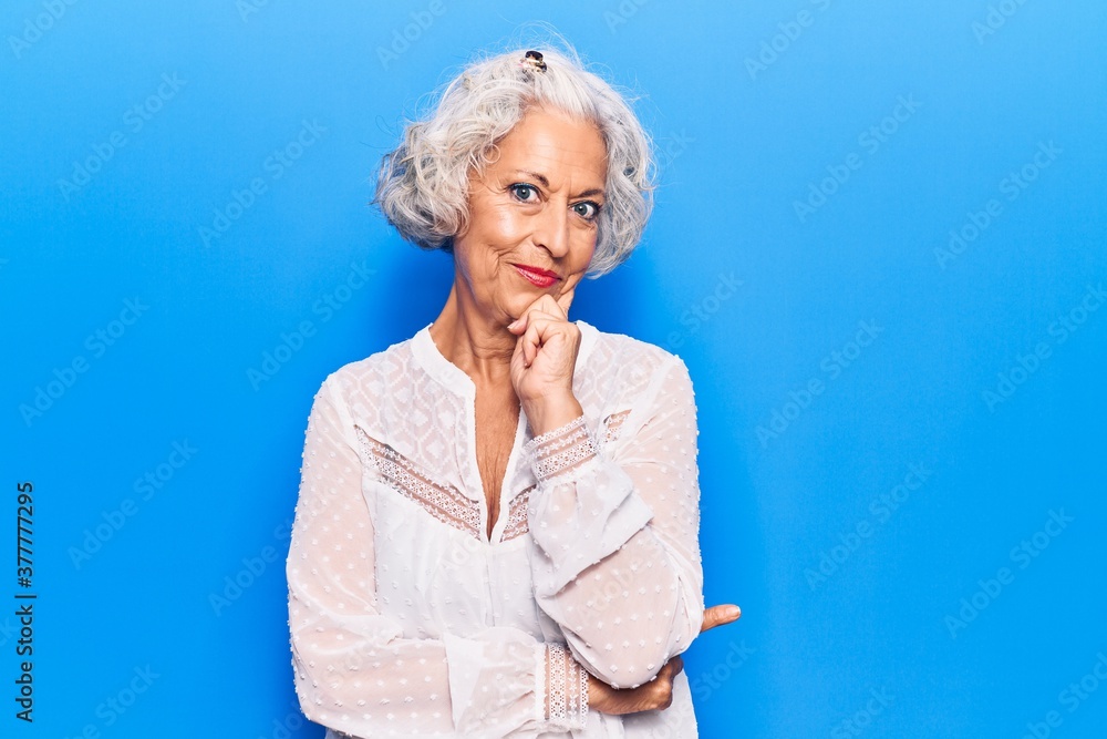 Senior grey-haired woman wearing casual clothes smiling looking confident at the camera with crossed arms and hand on chin. thinking positive.