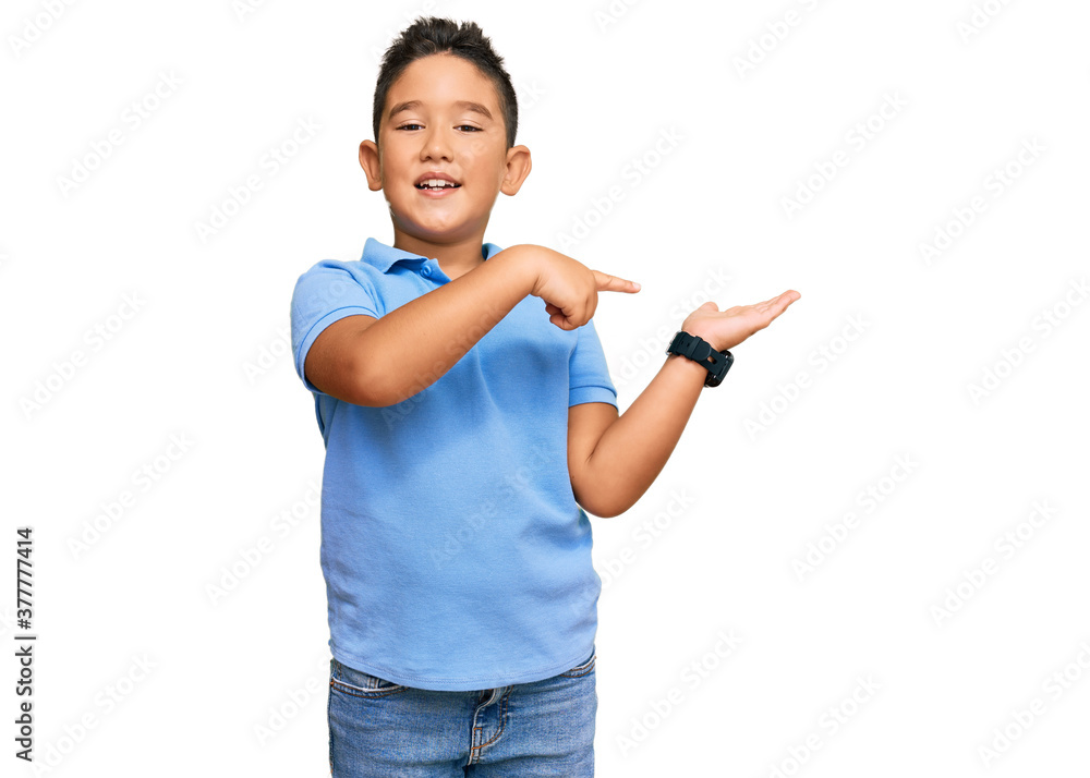 Little boy hispanic kid wearing casual clothes amazed and smiling to the camera while presenting with hand and pointing with finger. Little boy hispanic kid wearing casual clothes amazed and smiling to the camera while presenting with hand and pointing with finger.