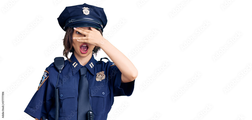 Young beautiful girl wearing police uniform peeking in shock covering face and eyes with hand, looking through fingers with embarrassed expression. Young beautiful girl wearing police uniform peeking in shock covering face and eyes with hand, looking through fingers with embarrassed expression.