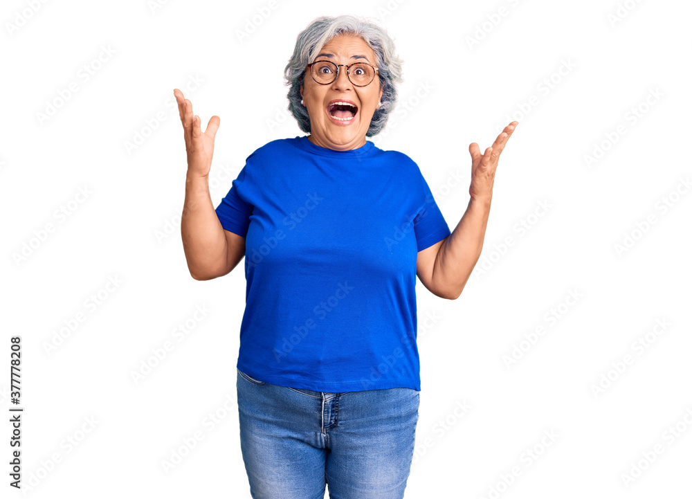 Senior woman with gray hair wearing casual clothes and glasses celebrating mad and crazy for success with arms raised and closed eyes screaming excited. winner concept Senior woman with gray hair wearing casual clothes and glasses celebrating mad and crazy for success with arms raised and closed eyes screaming excited. winner concept