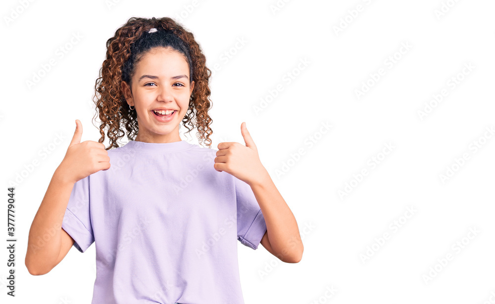 Beautiful kid girl with curly hair wearing casual clothes success sign doing positive gesture with hand, thumbs up smiling and happy. cheerful expression and winner gesture. Beautiful kid girl with curly hair wearing casual clothes success sign doing positive gesture with hand, thumbs up smiling and happy. cheerful expression and winner gesture.