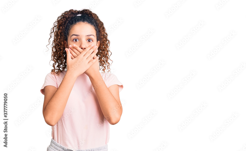 Beautiful kid girl with curly hair wearing casual clothes shocked covering mouth with hands for mistake. secret concept. Beautiful kid girl with curly hair wearing casual clothes shocked covering mouth with hands for mistake. secret concept.