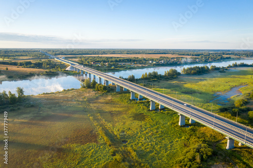 Early morning landscape. Foggy river. Highway bridge across the Volkhov river. River valley in the morning fog at sunrise. View from above. Rays of the sun breaking through the fog in over the trees