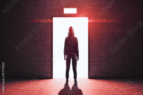 Hacker stands in front of an open elevator door from whicha red light emanates.