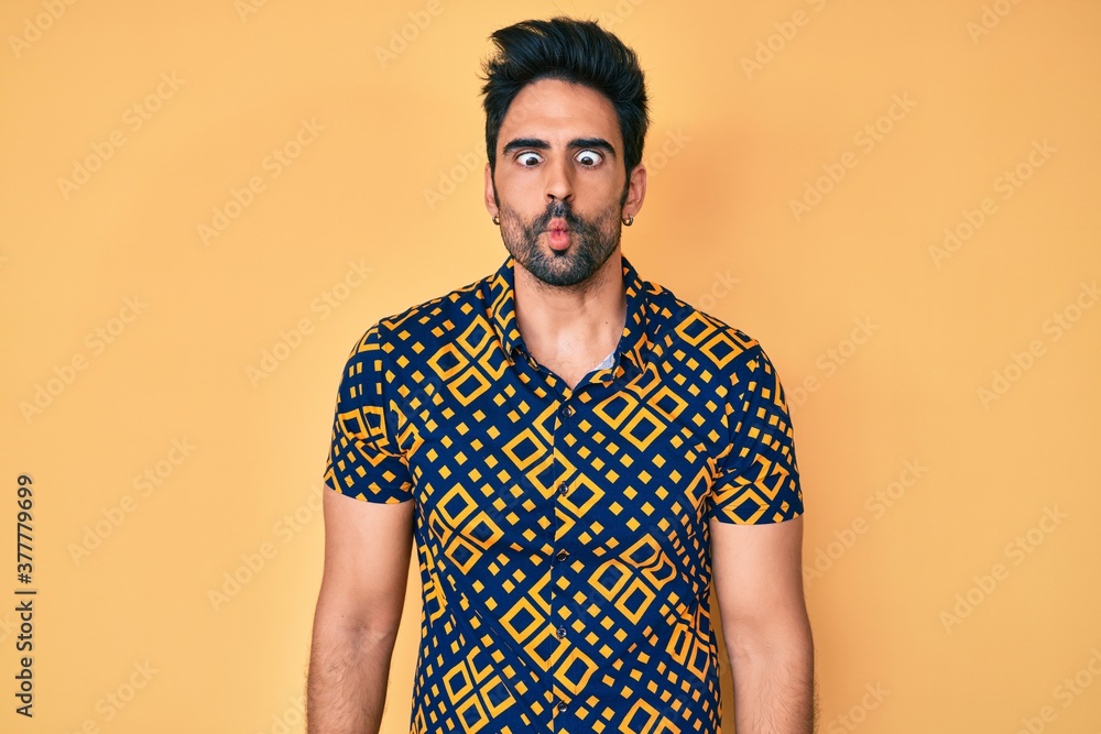 Handsome hispanic man with beard wearing 80s disco style shirt making fish face with lips, crazy and comical gesture. funny expression. Handsome hispanic man with beard wearing 80s disco style shirt making fish face with lips, crazy and comical gesture. funny expression.