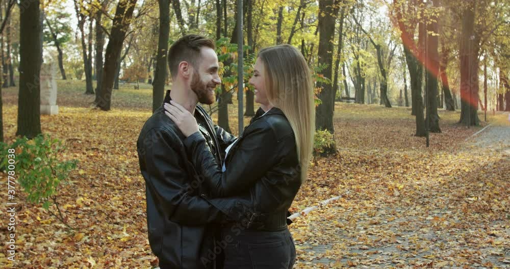Lovely couple laughing and having fun while standing in embraces in autumn park Lovely couple laughing and having fun while standing in embraces in autumn park