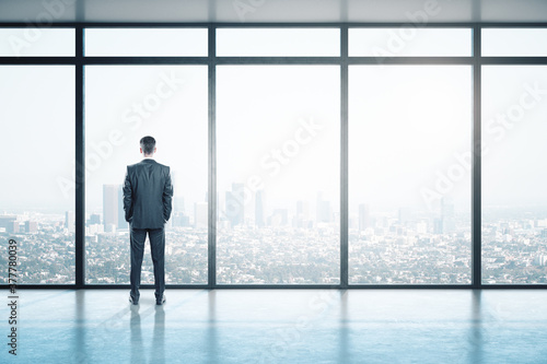 Young businessman looking on window in contemporary empty office