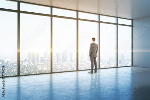 Businessman looking to window in office hall