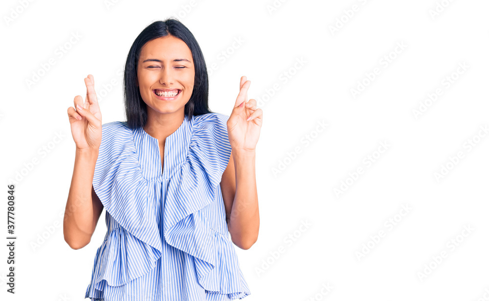 Young beautiful latin girl wearing casual clothes gesturing finger crossed smiling with hope and eyes closed. luck and superstitious concept. Young beautiful latin girl wearing casual clothes gesturing finger crossed smiling with hope and eyes closed. luck and superstitious concept.
