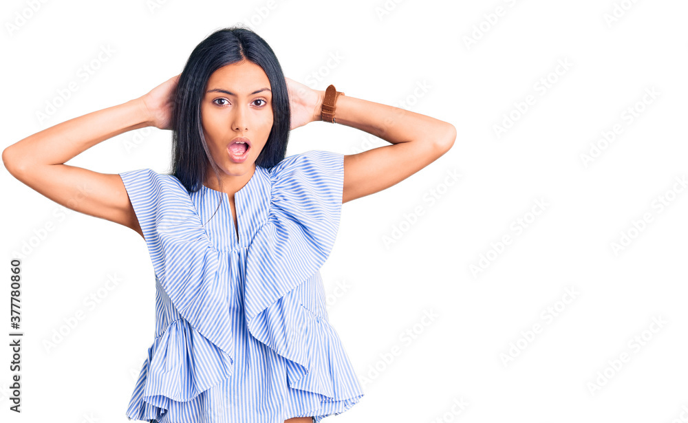 Young beautiful latin girl wearing casual clothes crazy and scared with hands on head, afraid and surprised of shock with open mouth Young beautiful latin girl wearing casual clothes crazy and scared with hands on head, afraid and surprised of shock with open mouth
