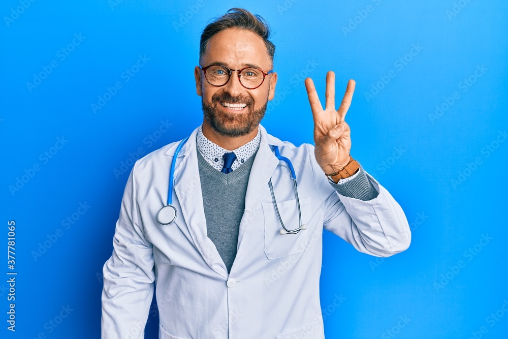 Handsome middle age man wearing doctor uniform and stethoscope showing and pointing up with fingers number three while smiling confident and happy. Handsome middle age man wearing doctor uniform and stethoscope showing and pointing up with fingers number three while smiling confident and happy.