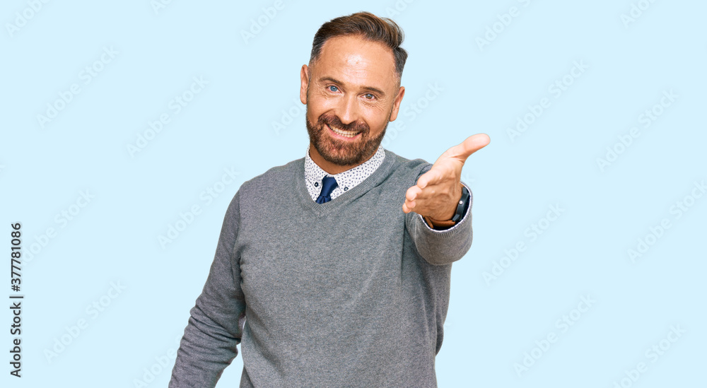 Handsome middle age man wearing business clothes smiling friendly offering handshake as greeting and welcoming. successful business. Handsome middle age man wearing business clothes smiling friendly offering handshake as greeting and welcoming. successful business.