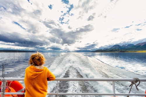 Child contemplates the landscape of the Beagle Channel from the stern of a ferry boat during a tour