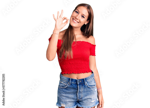 Young beautiful hispanic woman wearing casual clothes smiling positive doing ok sign with hand and fingers. successful expression.