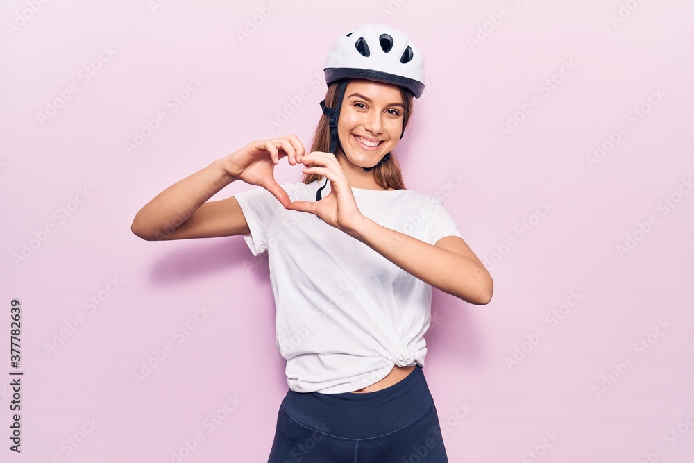 Young beautiful girl wearing bike helmet smiling in love doing heart symbol shape with hands. romantic concept. Young beautiful girl wearing bike helmet smiling in love doing heart symbol shape with hands. romantic concept.
