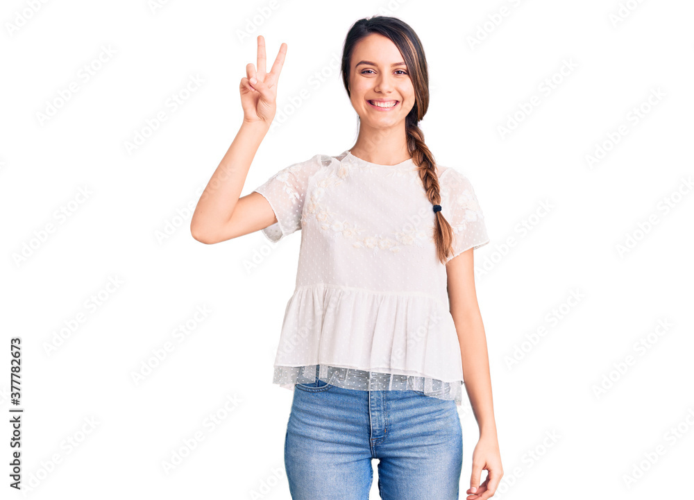 Young beautiful girl wearing casual t shirt smiling with happy face winking at the camera doing victory sign. number two. Young beautiful girl wearing casual t shirt smiling with happy face winking at the camera doing victory sign. number two.