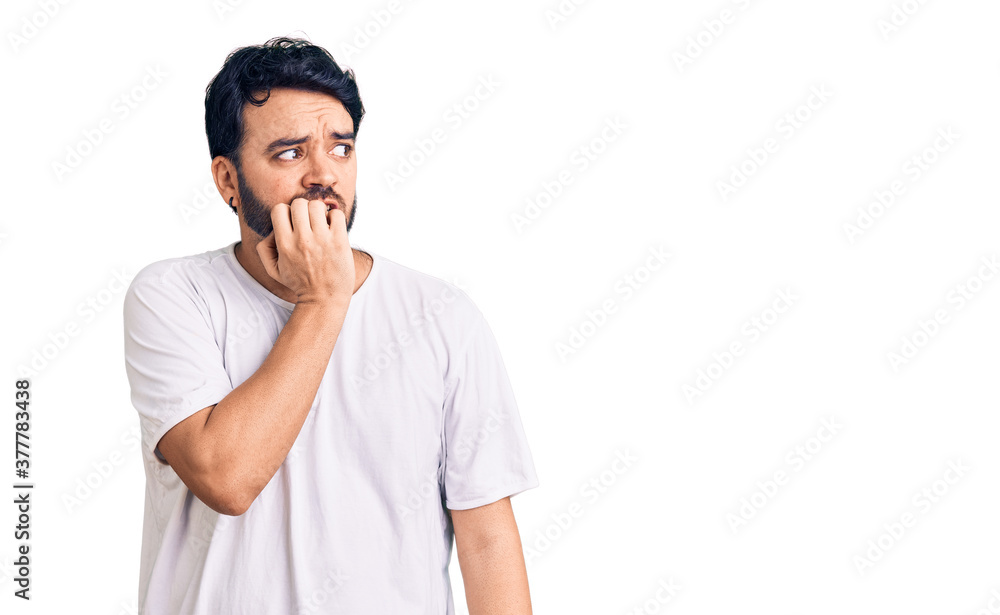 Young hispanic man wearing casual clothes looking stressed and nervous with hands on mouth biting nails. anxiety problem. Young hispanic man wearing casual clothes looking stressed and nervous with hands on mouth biting nails. anxiety problem.