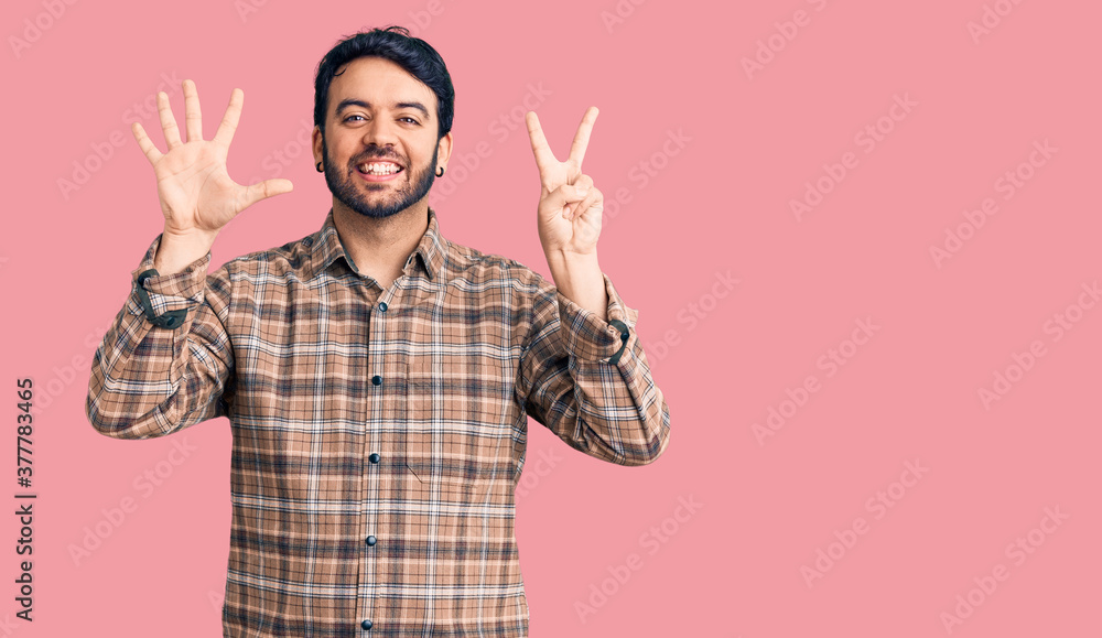 Young hispanic man wearing casual clothes showing and pointing up with fingers number seven while smiling confident and happy. Young hispanic man wearing casual clothes showing and pointing up with fingers number seven while smiling confident and happy.