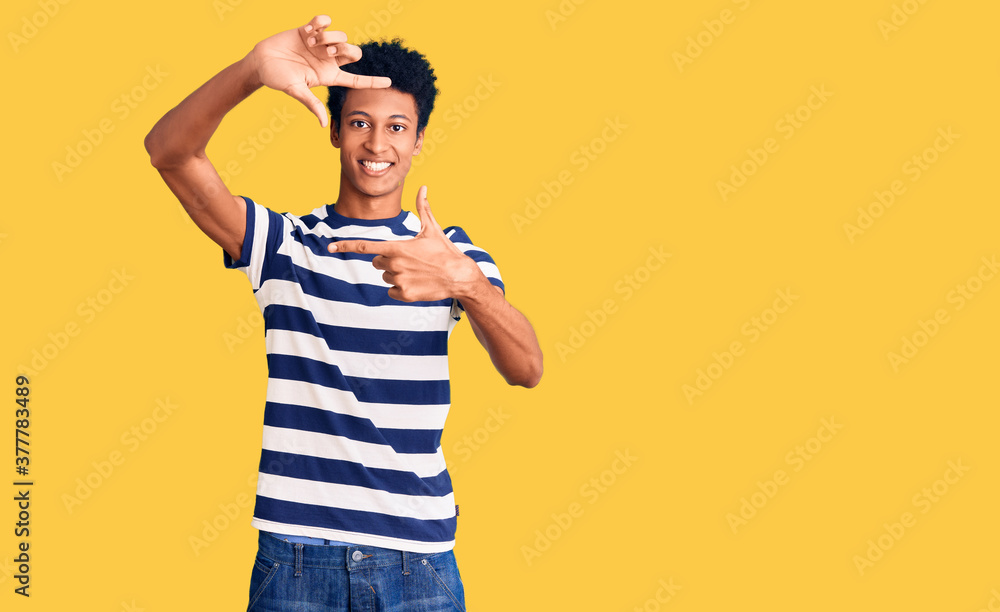 Young african american man wearing casual clothes smiling making frame with hands and fingers with happy face. creativity and photography concept. Young african american man wearing casual clothes smiling making frame with hands and fingers with happy face. creativity and photography concept.